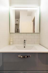 ein Bad mit einem Waschbecken und einem Spiegel in der Unterkunft L'Aquarelle - Studio cosy proche du métro in Toulouse