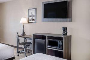 a hotel room with a desk and a television on a wall at Ramada by Wyndham Rome - Verona in Rome
