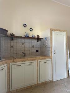 a kitchen with white cabinets and a white door at La casa di Giovanna in Lampedusa