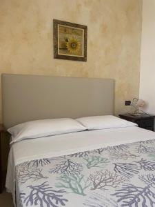 La casa di Giovanna في لامبيدوسا: غرفة نوم بسرير مع صورة زهرة على الحائط