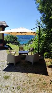 a picnic table and two chairs under an umbrella at WALDHAUS HIRSCH Bungalow only for you self check in in Pörtschach am Wörthersee