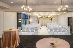 ein Zimmer mit einer Reihe weißer Stühle und einem Zimmer mit einer Reihe von Tischen in der Unterkunft Courtyard by Marriott Calgary South in Calgary