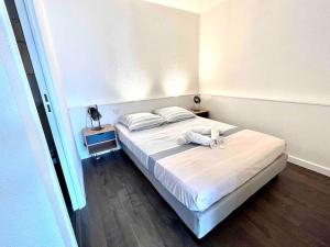 een slaapkamer met een bed met witte lakens en kussens bij T1bis avec terrasse et parking privés LE MIAMI in Perpignan