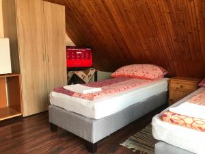 two twin beds in a room with wooden walls at Marika Vendégház in Szeged