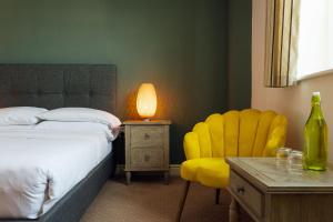 een slaapkamer met een bed en een gele stoel bij The Imperial Dragon Hotel in Saundersfoot