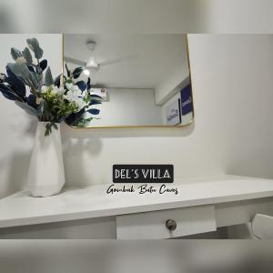 a vase of flowers on a shelf with a mirror at Dels Villa with private pool near UIA Batu Caves Gombak in Batu Caves