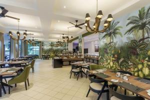 um restaurante com mesas e cadeiras e palmeiras na parede em Protea Hotel by Marriott Livingstone em Livingstone