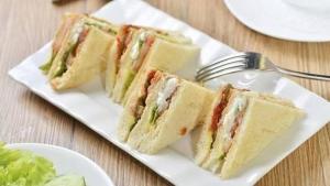 two sandwiches on a white plate with a fork at 9 Residences Seminyak in Seminyak