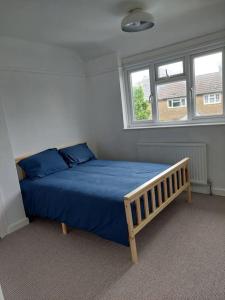 um quarto com uma cama com lençóis azuis e duas janelas em Lovely 3 bed terraced family house em Kew Gardens