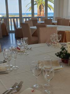 una mesa con copas de vino en un mantel blanco en Hotel Il Timone, en Specchiolla