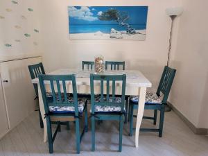 uma mesa de jantar com 4 cadeiras, uma mesa e um quadro em Villa La Pelosa Stintino em Stintino