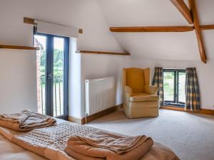 a bedroom with a bed and a chair and windows at Oak Barn in Felbrigg