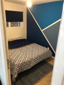 una piccola camera con un letto con una parete blu di Maisonnette à la campagne rivière SPA et détente a Saint-Seriès