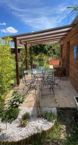 een patio met een tafel en stoelen onder een pergola bij Maisonnette à la campagne rivière SPA et détente in Saint-Seriès