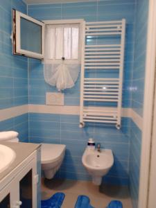 bagno piastrellato blu con servizi igienici e lavandino di Sweet home tra i due mari a Taranto