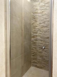 a shower with a glass door and a stone wall at Ennstal Classic Landhaus Chalet in Irdning