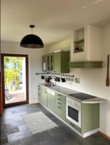 een keuken met groene kasten en een groot raam bij Ennstal Classic Landhaus Chalet in Irdning