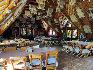 een eetkamer met tafels en stoelen en houten plafonds bij Pensiunea La Mogan in Moieciu de Jos