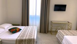 una camera d'albergo con due letti e una televisione di Chiostro San Francesco - Casa di Ospitalità Religio sa a Napoli