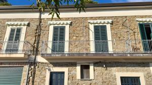 a stone building with green shutters and a balcony at Appartamento Pollica in Pollica