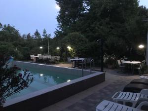 a swimming pool at night with tables and chairs at Marika Vendégház in Szeged