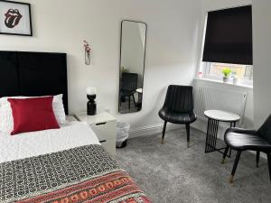 1 dormitorio con cama, espejo y sillas en En-suite Room 6-mins walk to Tooting Broadway Tube Station, en Londres