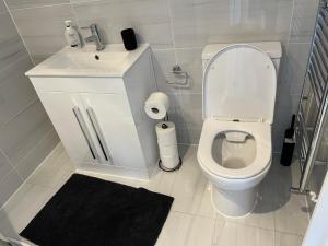 La salle de bains est pourvue de toilettes blanches et d'un lavabo. dans l'établissement En-suite Room 6-mins walk to Tooting Broadway Tube Station, à Londres