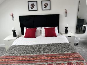 una camera da letto con un grande letto con cuscini rossi di En-suite Room 6-mins walk to Tooting Broadway Tube Station a Londra