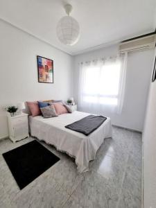 a white bedroom with a bed and a window at TorreSol Apartment in Torrevieja