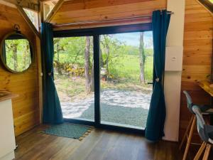 a sliding glass door in a cabin with a view of a yard at Chalet Dalo cosy spa privé in Roussayrolles