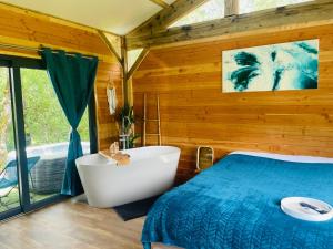 a bedroom with a tub and a bed with a blue blanket at Chalet Dalo cosy spa privé in Roussayrolles