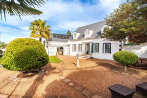 a white house with a palm tree at Cosimi Guest House in Durbanville