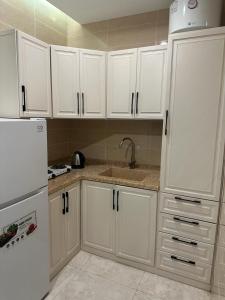 a kitchen with white cabinets and a sink and a refrigerator at دارك للوحدات السكنية in ‘Aryam