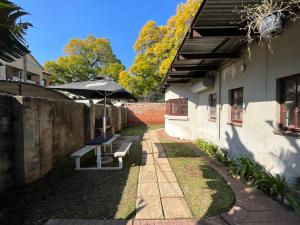 eine Terrasse mit einem Sonnenschirm und einer Bank neben einem Gebäude in der Unterkunft Casa Bravo - Cozy Traveller in Pretoria