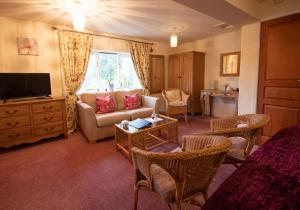 a living room with a couch and a tv at Magpies Lodge in Slinfold