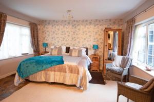 a bedroom with a bed and a chair and windows at Magpies Lodge in Slinfold