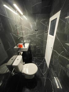 Baño de azulejos negros con aseo y lavamanos en Vila Efor, en Eforie Nord