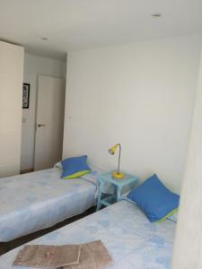 a bedroom with two beds and a table with a lamp at Casa Katze, 2 dormitorios, céntrica, playa y descanso in Carboneras