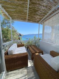een balkon met rieten meubels en uitzicht op de oceaan bij Casa del Mar Milos in Kástron