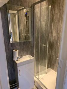 a bathroom with a shower and a sink and a mirror at Fabulous 4 bed 4 bath right by Luton Airport in Luton