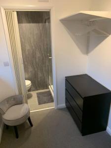 a bathroom with a black dresser and a chair and a shower at Fabulous 4 bed 4 bath right by Luton Airport in Luton