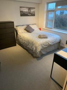 ein Schlafzimmer mit einem Bett, einer Kommode und einem Fenster in der Unterkunft Fabulous 4 bed 4 bath right by Luton Airport in Luton