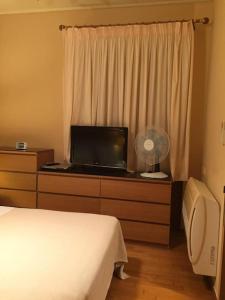 a bedroom with a bed and a dresser with a television at Small apartment near Athens Airport in Pikérmion