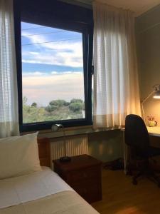 een slaapkamer met een raam, een bed en een bureau bij Small apartment near Athens Airport in Pikérmion
