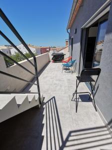 eine Terrasse mit 2 Stühlen und einem Treppengeländer in der Unterkunft AS22351 - P3 au 2ème et dernier étage dans une résidence neuve en Centre Ville in Le Grau-du-Roi