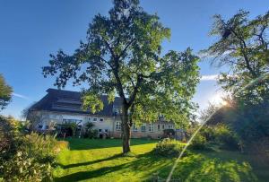 una casa grande con un árbol en el patio en Auszeit auf dem Drachenhof, das Hyggehaus, en Plattenburg