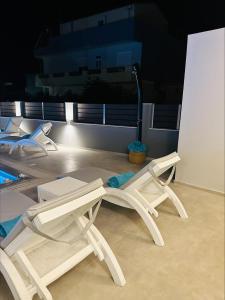 two white chairs and a table with a vacuum at Flev's Luxury House with pool in Kremasti +25 photos
