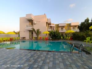 a swimming pool in front of a building at Raigad Srushti Beach near Resort in Alibaug