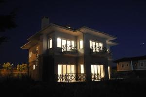 een groot huis met 's nachts de lichten aan bij A Scenic villa near Airport in Buyukcekmece