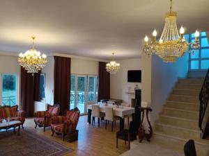 een woonkamer met kroonluchters en een tafel en stoelen bij A Scenic villa near Airport in Buyukcekmece